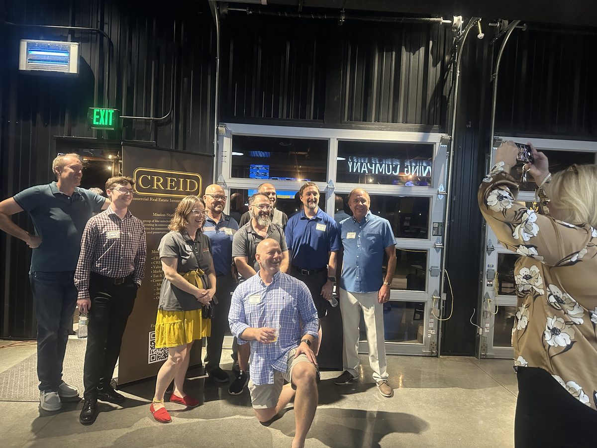 Group photo in front of the CREID banner at the 2025 mixer